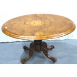 A 19th century burr walnut oval breakfast table, inlaid with tilting top and carved quadripartide