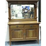 An Arts and Crafts period oak dresser with mirrored back, cupboard base and three bottle