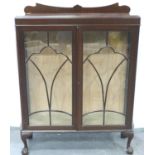 An early 20th century mahogany two door display cabinet, with bowed sides and claw and ball