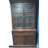 A Victorian bookcase, having two doors glazed with stained glass, three shelves raised above a