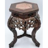 A padouk wood profusely carved vase stand, the top inset with a hexagonal panel of rouge marble, the