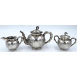 An export silver three-piece tea service, heavily embossed with floral detail and bamboo style