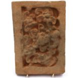 A Song Dynasty red clay tile, decorated in relief with a stylised front-facing dragon, 18 x 26 cm.