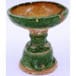 A Ming Dynasty glazed white clay pedestal, having a bowl form top supported on a shaped stand,