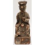 A Ming Dynasty carved wood figure of a seated official with cup, still retaining some of its