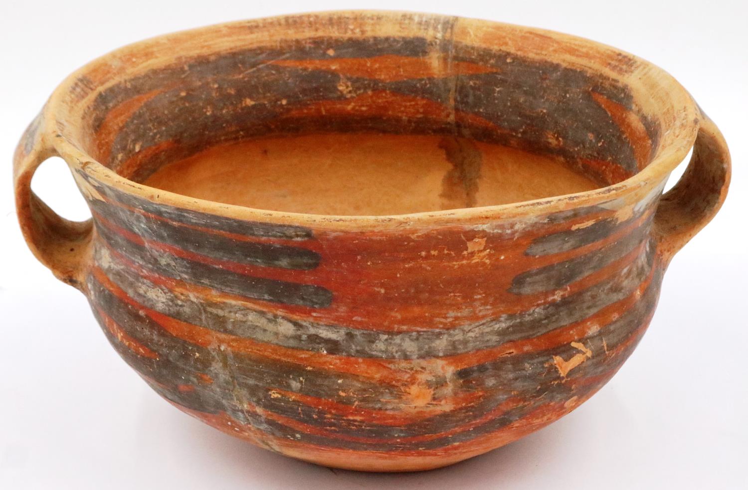 A Neolithic period terracotta bowl, having twin ring handles and flared rim, retaining most of its