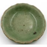 Ming Dynasty celadon shallow dish, having a wave border, imperfection beneath glaze, D: 13 cm. P&P