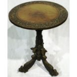 A heavily carved circular Anglo-Indian lamp table on a tripod base with mythical beasts to feet,