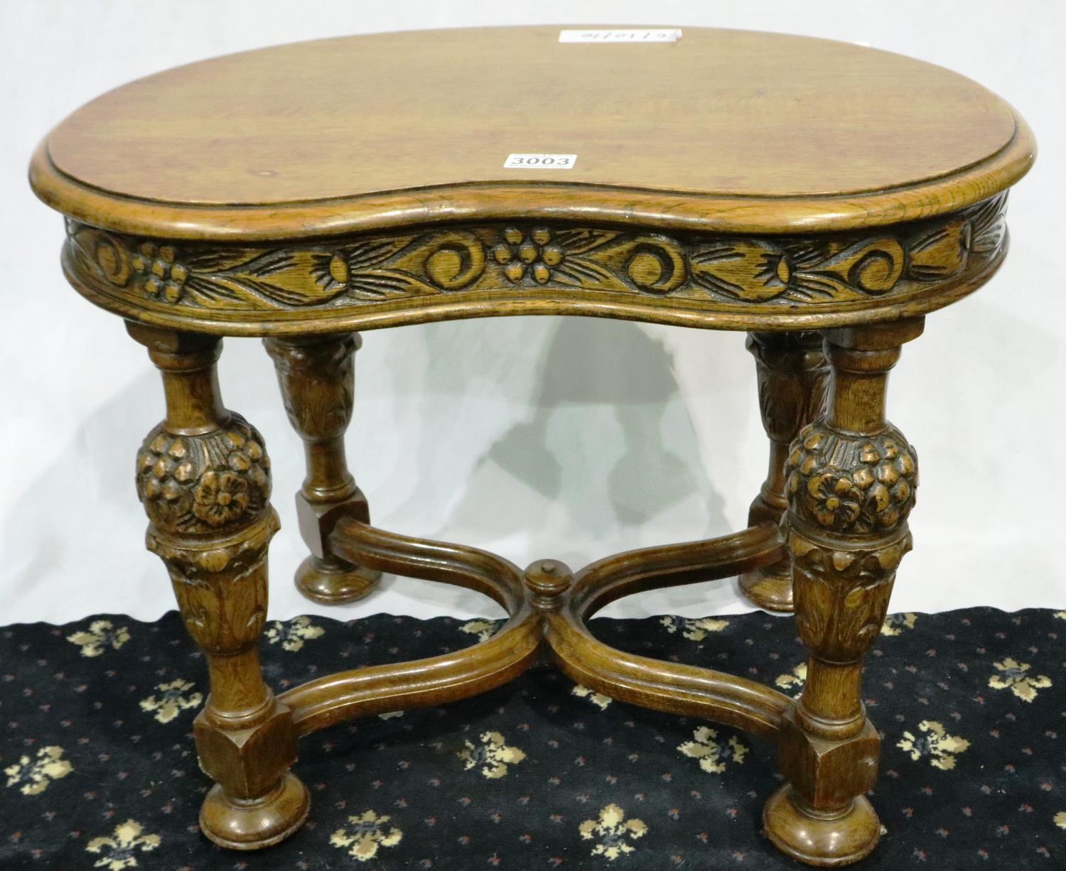 A 20th century kidney shaped lamp table in oak, with heavily carved bulbous, supports and shaped