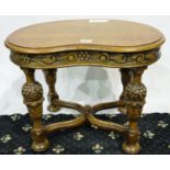 A 20th century kidney shaped lamp table in oak, with heavily carved bulbous, supports and shaped