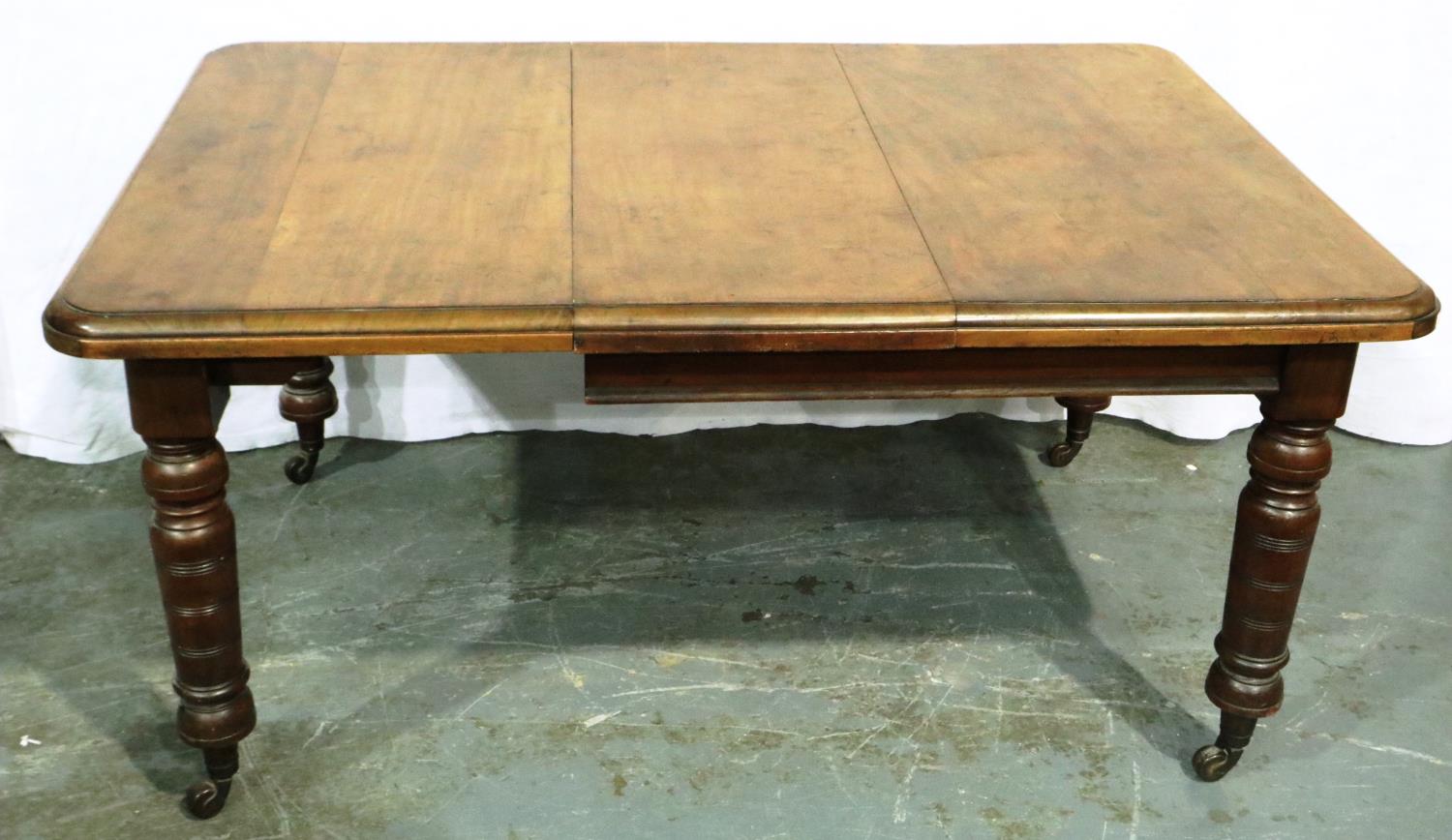 A Victorian walnut wind out extending dining table having one additional leaf and turned supports,