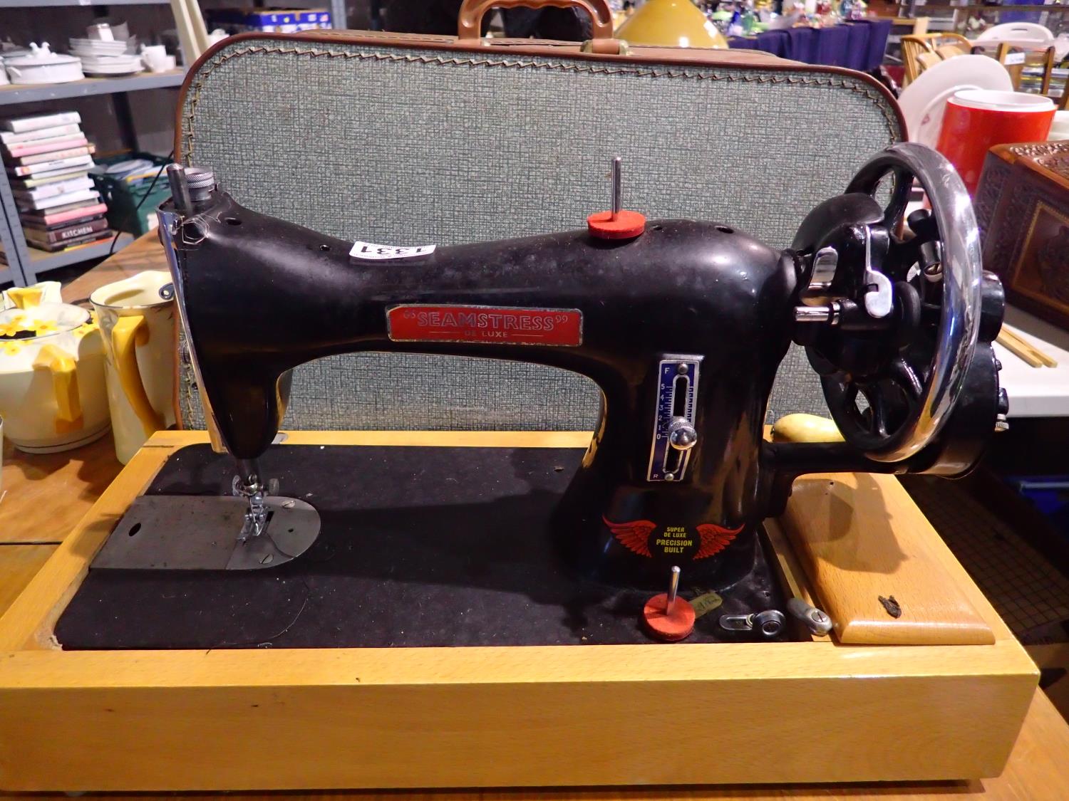 Seamstress Super Deluxe cased sewing machine. scuffs to body, hand crank is stiff but does rotate,