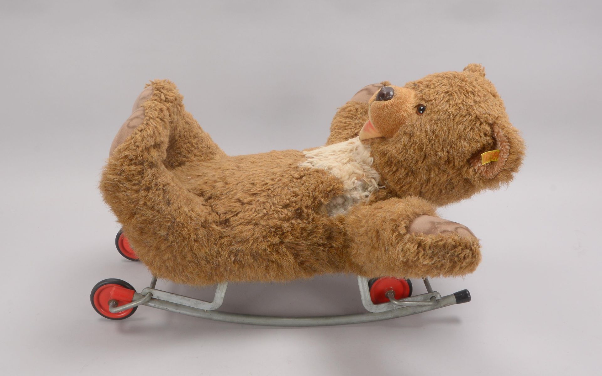 Gro&szlig;er Steiff-Teddyb&auml;r, auf Schaukel mit R&auml;dern; H&ouml;he 28 cm, L&auml;nge 60 cm (