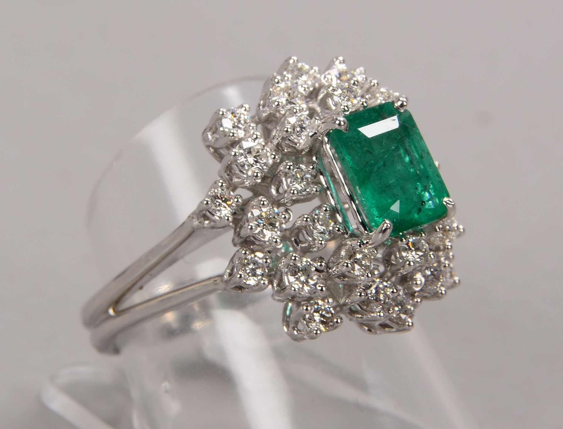 Ring, 750 WG, besetzt mit einzelnem Smaragd von ca. 1,39 ct, mit einer Entourage aus Brillanten/zusa