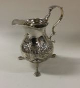 A good chased silver cream jug with floral decorat