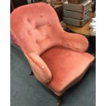 A pink upholstered button back armchair.