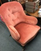 A pink upholstered button back armchair.