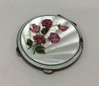 A silver and enamel compact with floral decoration