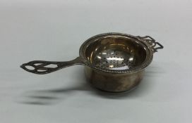 A chased silver tea strainer on stand with pierced
