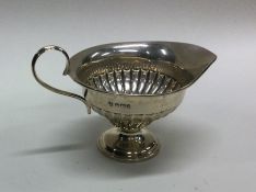 A small silver half fluted cream jug on pedestal f