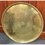 A large circular brass charger with chased decorat
