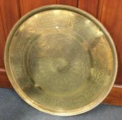 A large circular brass charger with chased decorat