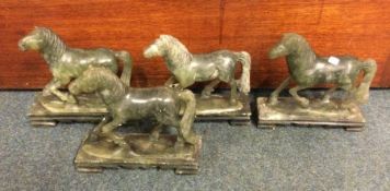 A set of four hard stone horses on matching bases.