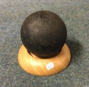 A 19th Century cannon ball on wooden stand. Est. £