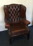 A leather button back wing armchair. Est. £50 - £8