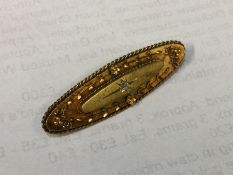 An oval gold boat shaped brooch inset with diamond