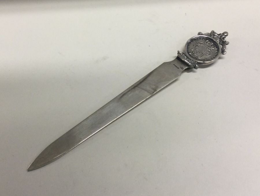 A silver letter opener inset with coin bearing import marks. Approx. 30 grams. Est. £25 - £35.