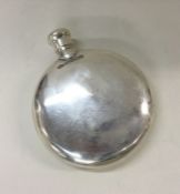 A heavy circular silver hip flask with screw-on co