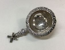 A small silver tea strainer mounted with a windmil