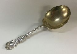 A chased silver serving spoon with embossed flower