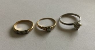 A group of three gold and diamond mounted rings. A