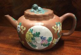 A Chinese terracotta teapot decorated with bright c