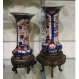 A pair of Imari vases on hard wood stands.