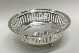 A small pierced silver bonbon dish on ball feet. A