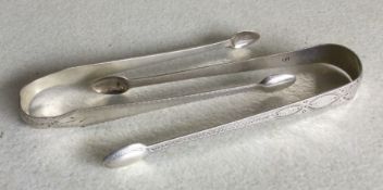 Two pairs of Georgian silver bright cut sugar tong