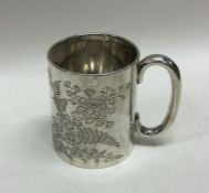 A silver christening mug engraved with leaves. She