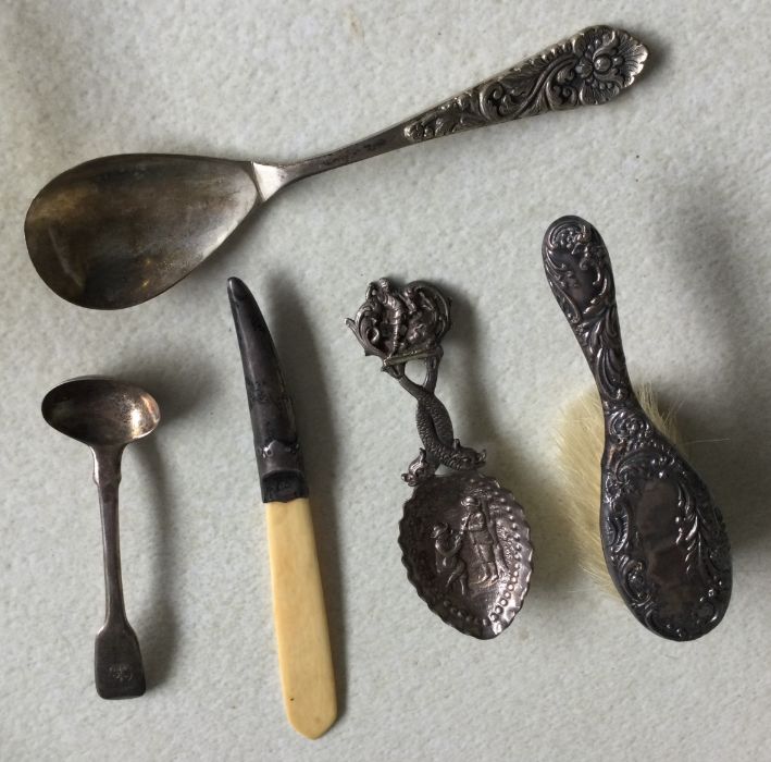 A silver caddy spoon decorated with figures togeth