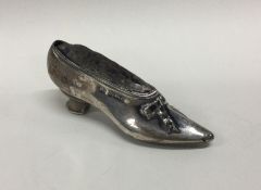 A small silver pin cushion in the form of a shoe.