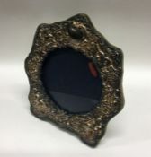 A silver and glass photo frame chased with cherubs