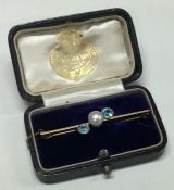 A pearl and blue stone brooch of crossover design.