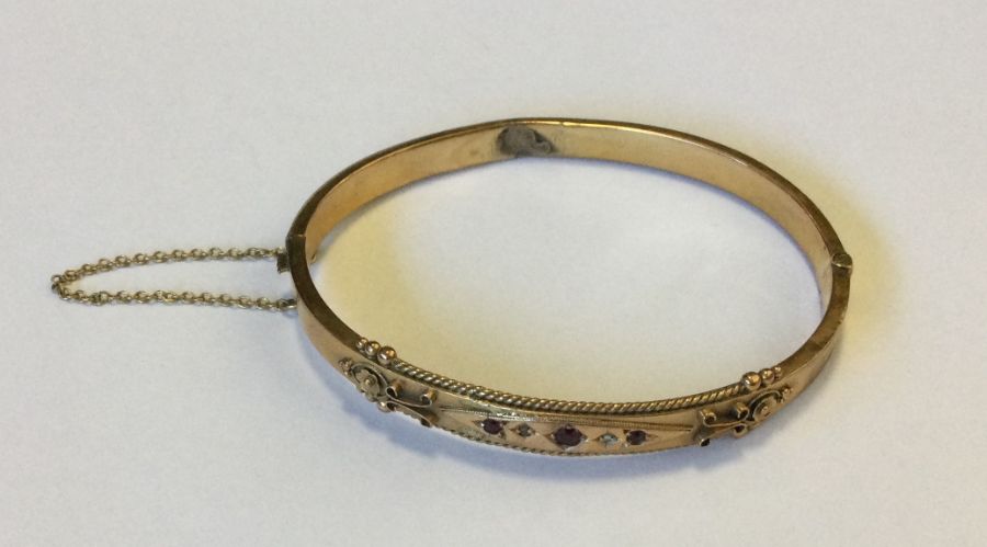 A heavy gold bangle mounted with gem stones. Appro