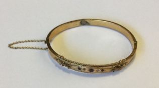 A heavy gold bangle mounted with gem stones. Appro