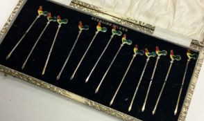 A set of twelve silver and enamel cocktail sticks.