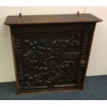 A carved oak single door cupboard.