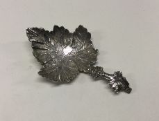A silver caddy spoon with leaf decoration. Birming