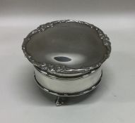 A circular silver ring box on ball and claw feet.